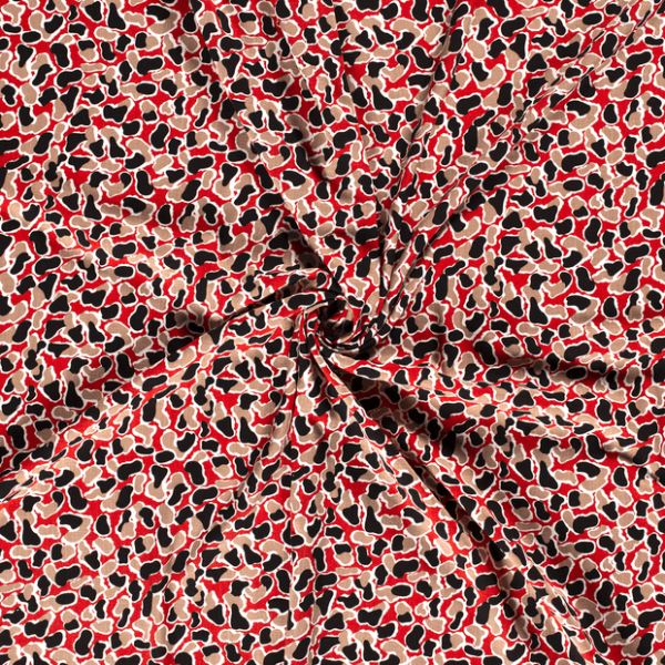 Tejido de viscosa con estampado de manchas sobre fondo rojo