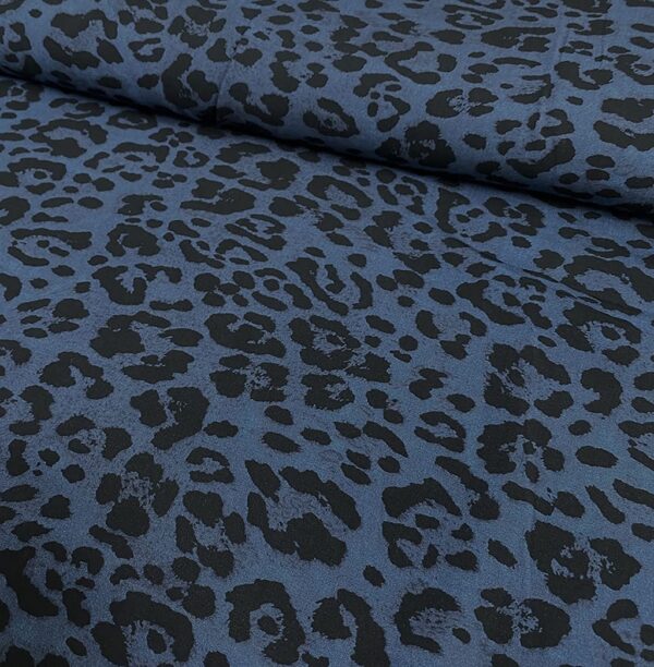 Tela de vestir de viscosa 100% estampado animal print de pantera con manchas en negro y fondo azul índigo.