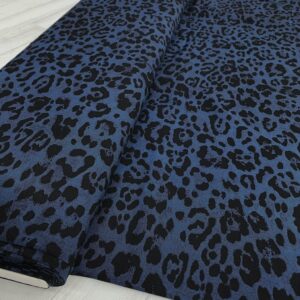 Tela de vestir de viscosa 100% estampado animal print de pantera con manchas en negro y fondo azul índigo.