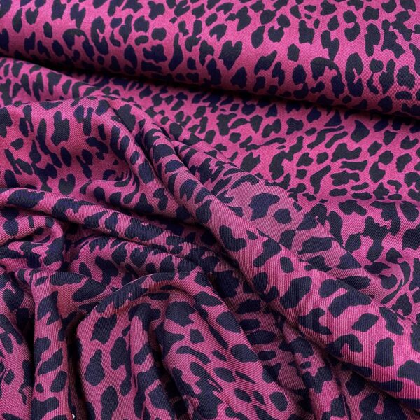 Tela de vestir de viscosa 100% tipo twill o sarga, con estampado animal print de leopardo con manchas en negro y fondo fucsia.