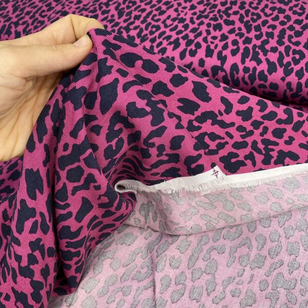 Tela de vestir de viscosa 100% tipo twill o sarga, con estampado animal print de leopardo con manchas en negro y fondo fucsia.