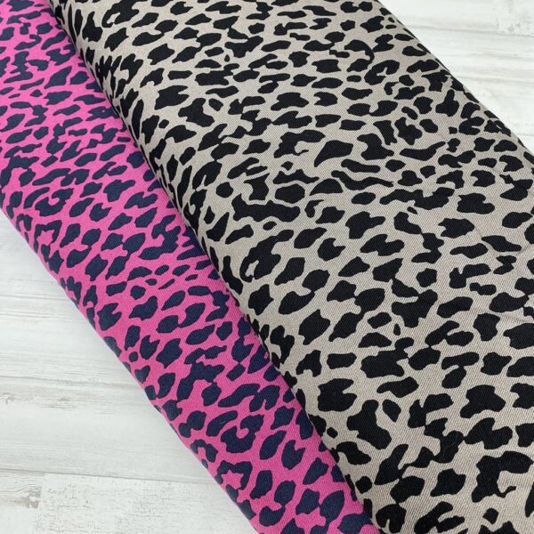 Tela de vestir de viscosa 100% tipo twill o sarga, con estampado animal print de leopardo con manchas en negro y fondo fucsia y gris claro.