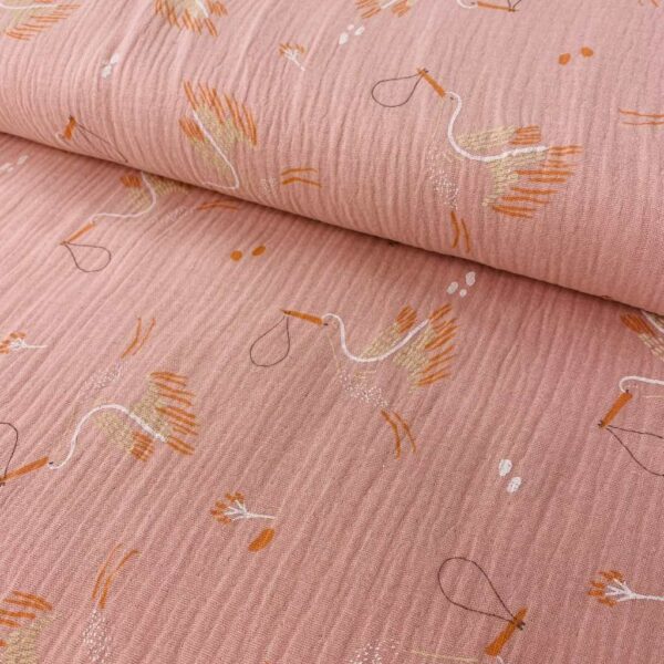 Tela de muselina o tela de doble gasa, algodón 100x100. Tejido con estampado de cigueñas fondo rosa.