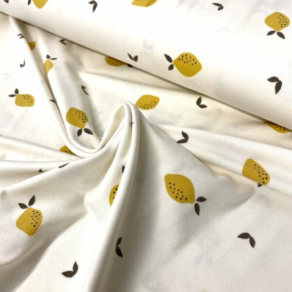 Tela de punto de camiseta de algodón orgánico tipo Jersey estampado silvestre con limones fondo crudo.