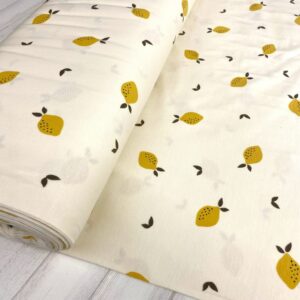 Tela de punto de camiseta de algodón orgánico tipo Jersey estampado silvestre con limones fondo crudo.