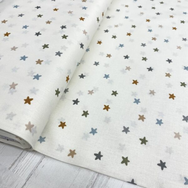 Tela de algodón estampada con estrellitas de colores fondo beige. Tela de algodón tipo popelín para todo tipo de creatividades de Patchwork, manualidades o confecciones creativas.