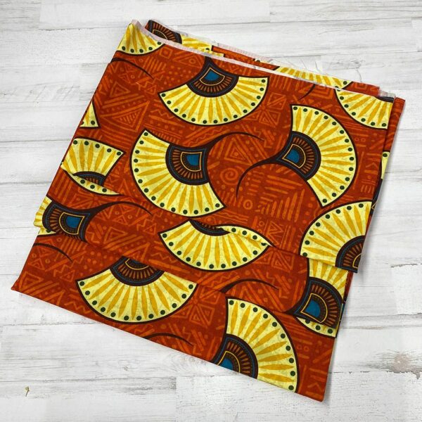 Loneta con estampado tipo africano wax con formas de abanicos amarillas y fondo teja. Con colores muy vivos. Tejido muy versátil y resistente. Ideal para todo tipo de manualidades.