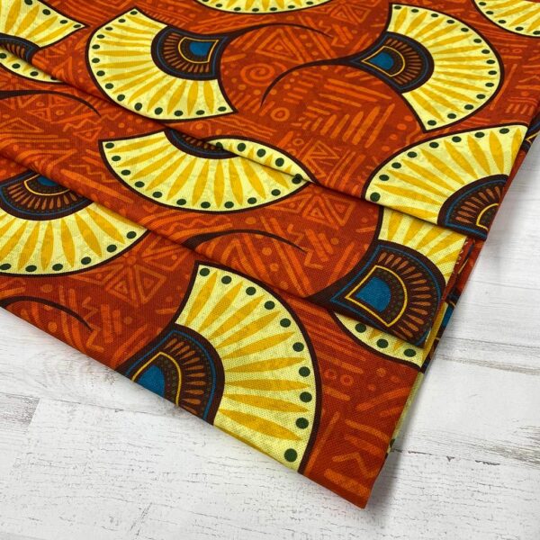Loneta con estampado tipo africano wax con formas de abanicos amarillas y fondo teja. Con colores muy vivos. Tejido muy versátil y resistente. Ideal para todo tipo de manualidades.