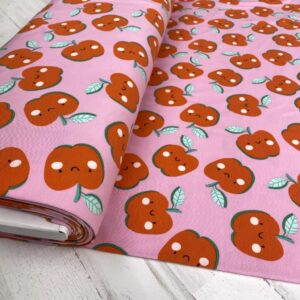 Tela de punto de camiseta de algodón orgánico. Tipo Jersey estampado con manzanas alegres fondo rosa fucsia.