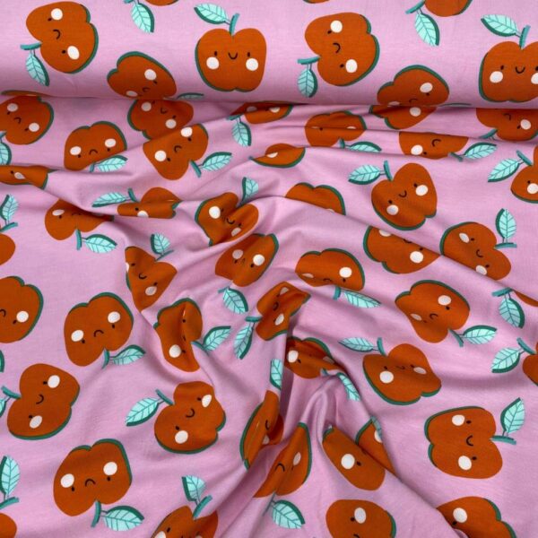 Tela de punto de camiseta de algodón orgánico. Tipo Jersey estampado con manzanas alegres fondo rosa fucsia.