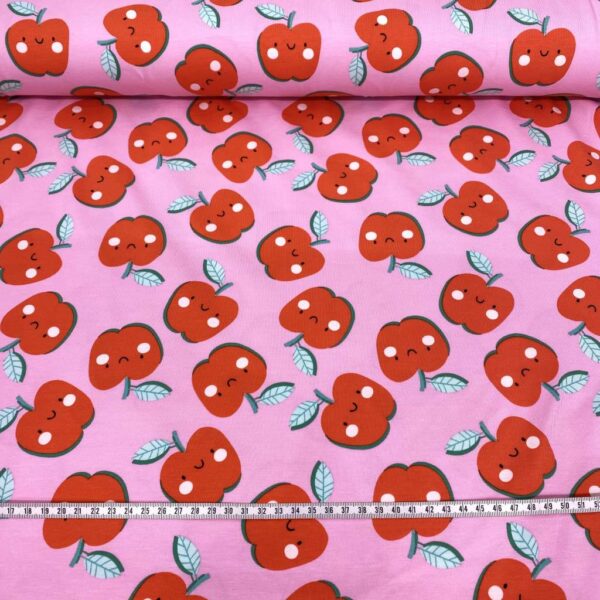 Tela de punto de camiseta de algodón orgánico. Tipo Jersey estampado con manzanas alegres fondo rosa fucsia.