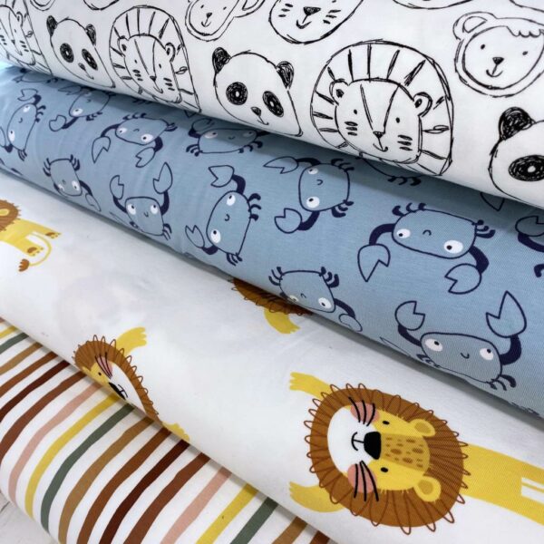 Tela de punto de camiseta de algodón orgánico. Tipo Jersey estampado con rallas, leones, cangrejos y osos panda fondo blanco roto