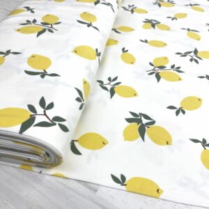 Tela de punto de camiseta de algodón orgánico. Tipo Jersey estampado con limones amarillos fondo blanco roto