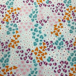 Tela de punto de camiseta de algodón orgánico. Tipo Jersey estampado con corazones en animal print fondo azul claro.