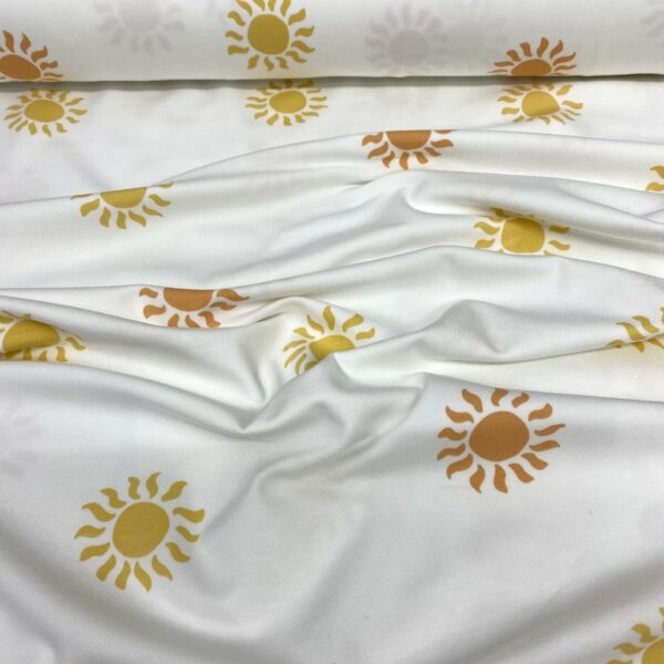 Tela de punto de camiseta de algodón orgánico. Tipo Jersey estampado con soles amarillos y naranjas fondo blanco roto
