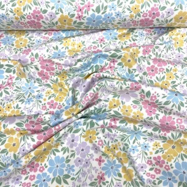 Tela de punto de camiseta de algodón orgánico. Tipo Jersey estampado con flores de colores fondo blanco roto.