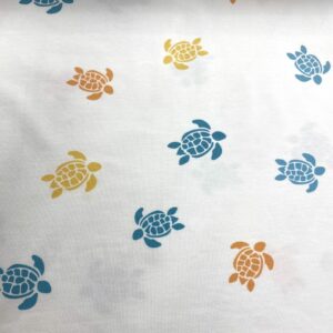 Tela de punto de camiseta de algodón orgánico. Tipo Jersey estampado con tortugas amarillas, naranjas y azules fondo blanco roto