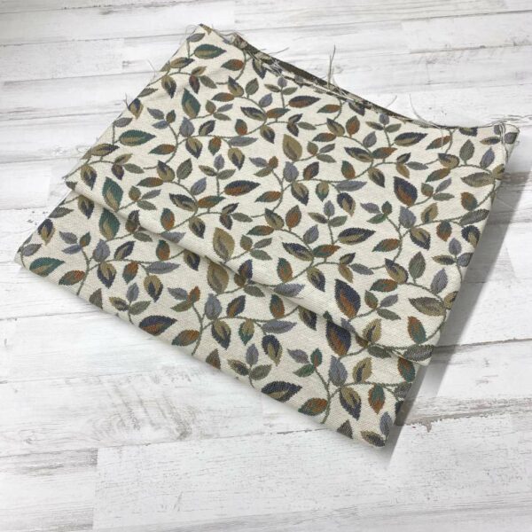 Retal de tela de tapicería gobelino estampado con hojas pequeñas en una rama.