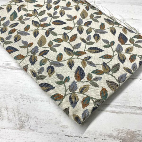 Retal de tela de tapicería gobelino estampado con hojas pequeñas en una rama.