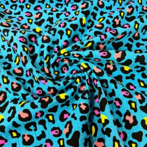 Tela con diseño de leopardo colorido en tonos vibrantes y fondo azul.