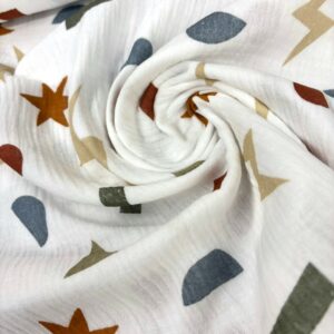 Muselina de algodón con estampado de estrellas y formas geométricas en colores tierra.