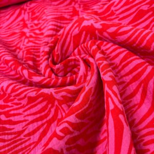 Muselina de animal print zebra en tonos rosas y rojos, ideal para confección y decoración.