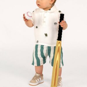 Niño pequeño con bate de béisbol y pelota en mano, listo para jugar en un fondo blanco.