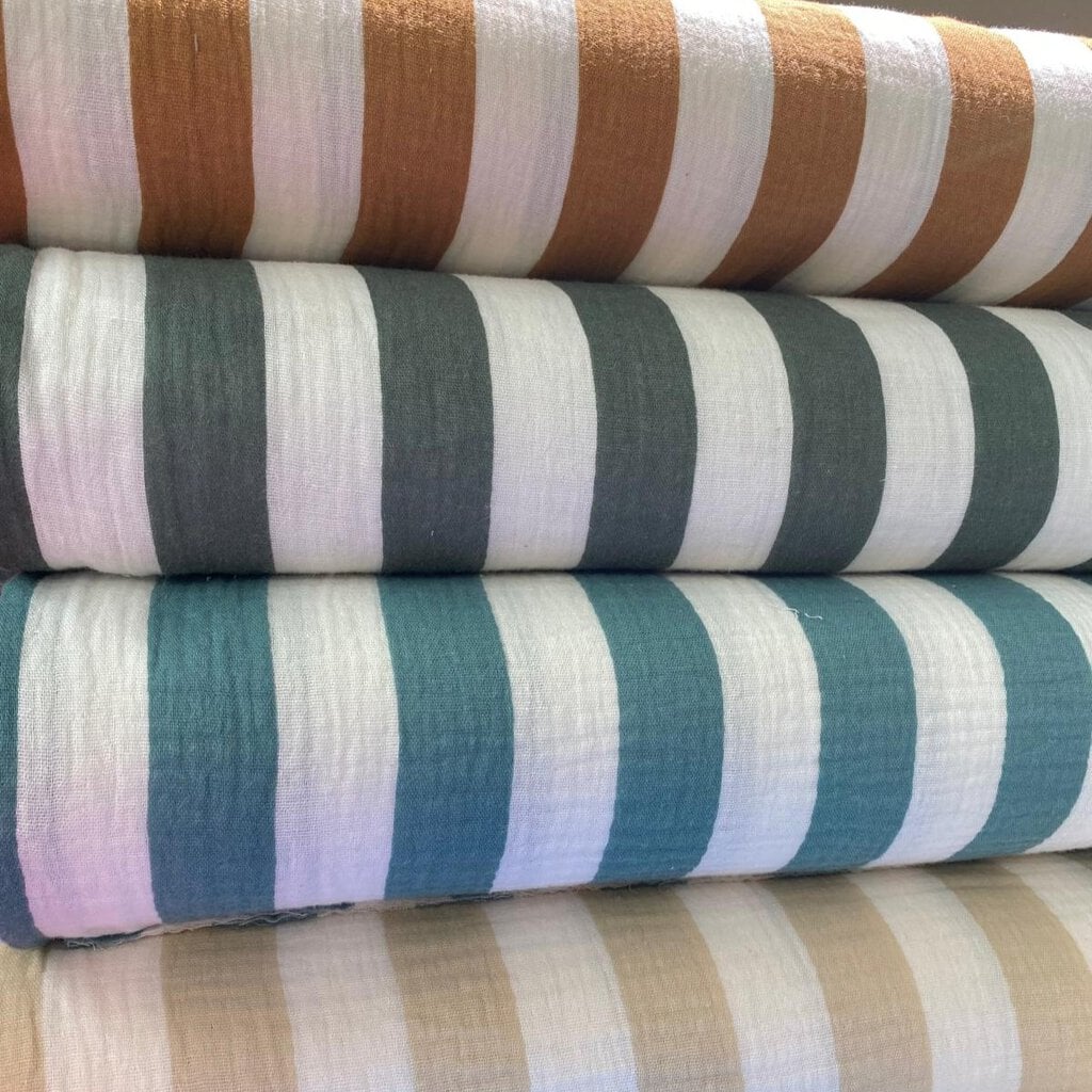 Rollo de tejidos de rayas en colores beige, gris y azul para cortinas y decoración en Granollers.